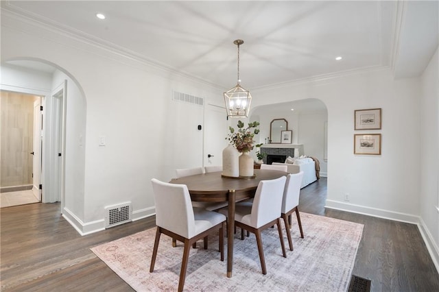 dining room featuring arched walkways, visible vents, and dark wood-style floors