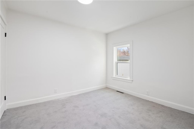 empty room with baseboards, light carpet, and visible vents