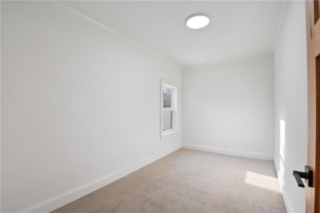 spare room with light colored carpet, crown molding, and baseboards