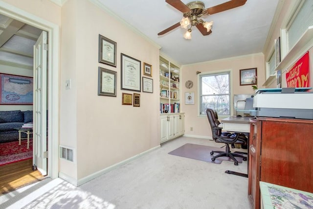 carpeted office space featuring visible vents, baseboards, a ceiling fan, and crown molding