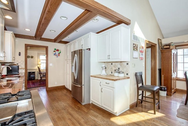 kitchen featuring light wood finished floors, stainless steel fridge, and white cabinetry