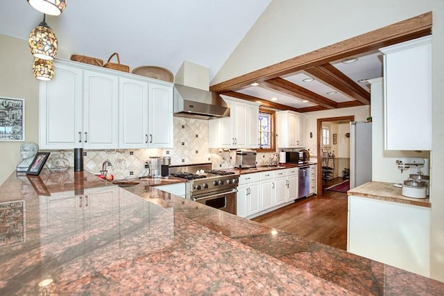 kitchen with decorative backsplash, appliances with stainless steel finishes, wall chimney range hood, and a sink