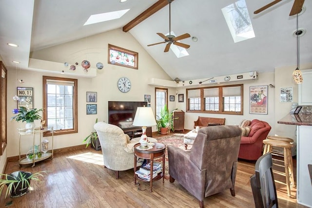 living room featuring ceiling fan, a wealth of natural light, a skylight, and wood finished floors