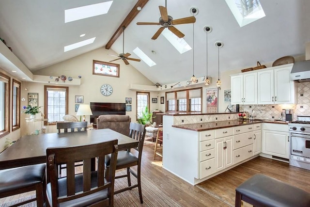 kitchen featuring stainless steel range, a skylight, dark wood-type flooring, and a peninsula