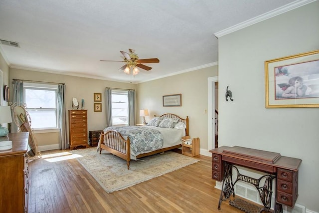 bedroom featuring baseboards, light wood-style floors, visible vents, and ornamental molding