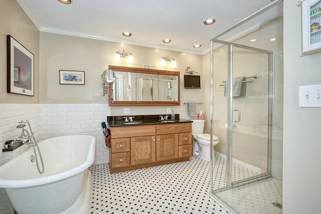 bathroom featuring vanity, a stall shower, ornamental molding, a freestanding bath, and tile walls