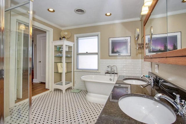 bathroom with a soaking tub, visible vents, ornamental molding, and a sink