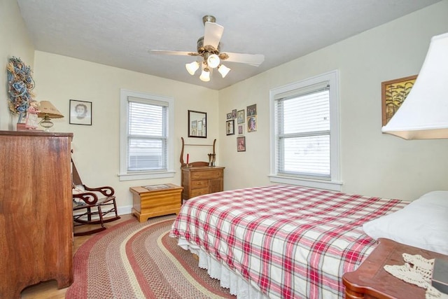 bedroom featuring a textured ceiling, multiple windows, baseboards, and ceiling fan