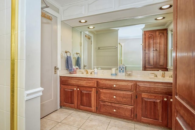 bathroom with tile patterned floors, crown molding, double vanity, and a sink