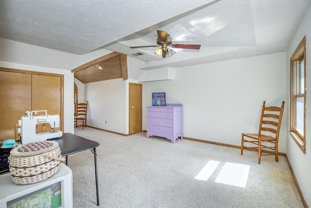 sitting room with light carpet, a textured ceiling, a ceiling fan, and baseboards