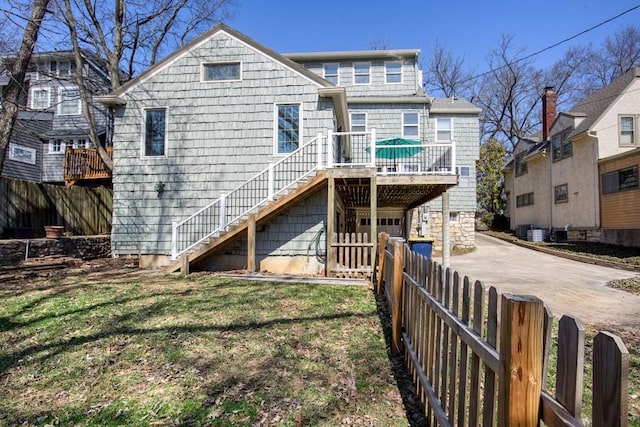 rear view of property featuring an attached garage, fence private yard, stairs, cooling unit, and driveway