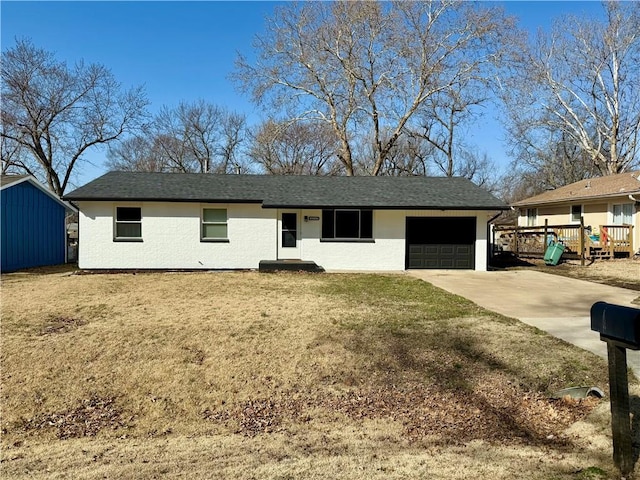 single story home featuring an attached garage, concrete driveway, a front lawn, and a shingled roof