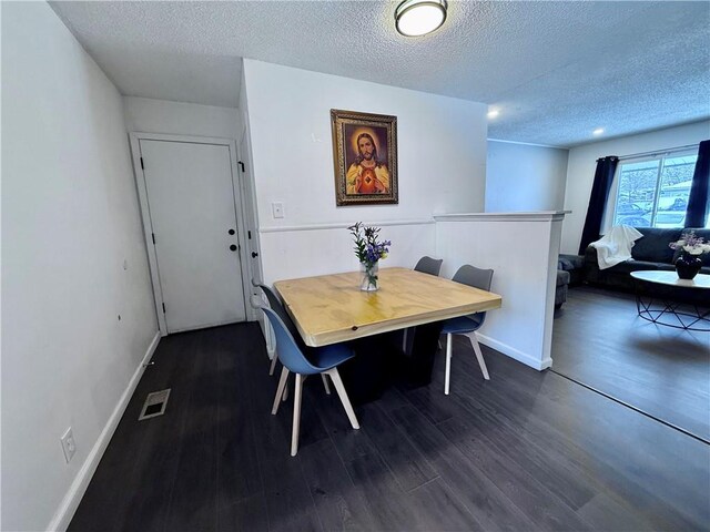 dining room with baseboards, dark wood-style floors, visible vents, and a textured ceiling