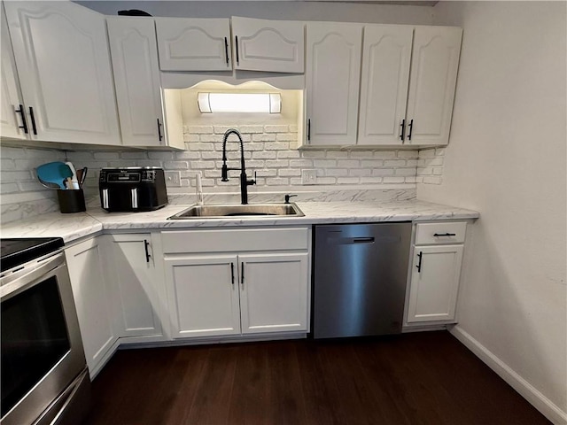 kitchen with a sink, appliances with stainless steel finishes, dark wood-style flooring, and white cabinetry