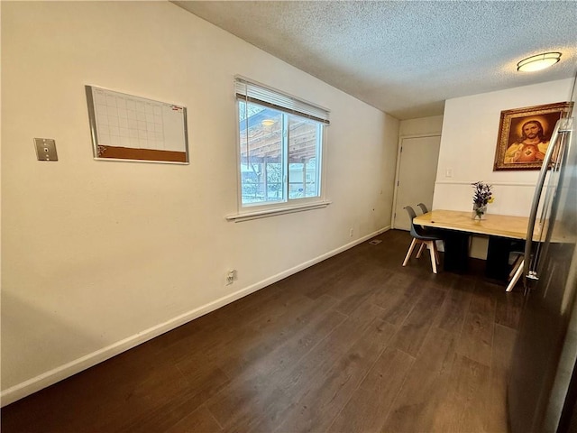 dining area featuring a textured ceiling, baseboards, and dark wood-style flooring