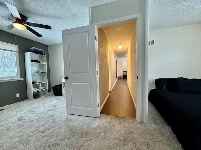 bedroom featuring visible vents, carpet floors, a textured ceiling, and a ceiling fan