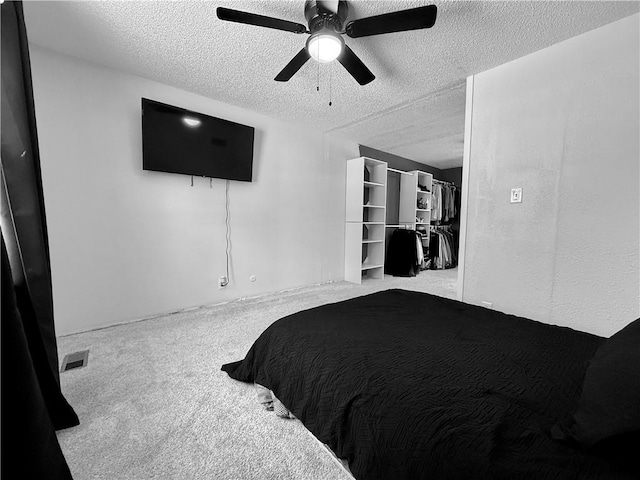 carpeted bedroom with ceiling fan, visible vents, and a textured ceiling