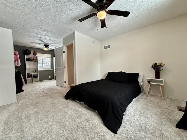 carpeted bedroom with a ceiling fan, visible vents, and a textured ceiling