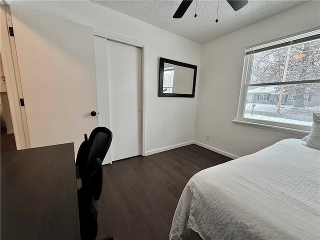 bedroom with dark wood finished floors, baseboards, a textured ceiling, and a closet