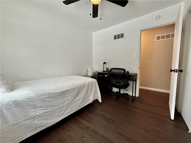 bedroom with a ceiling fan, wood finished floors, visible vents, and a textured ceiling