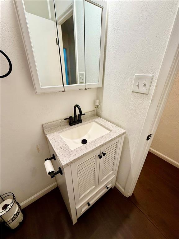 bathroom featuring vanity, wood finished floors, and baseboards