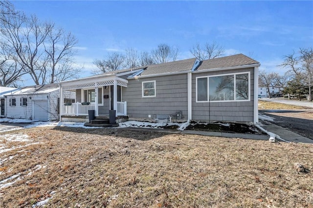 view of front of property featuring a shingled roof, covered porch, and a garage