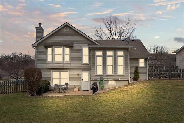 rear view of house featuring a yard, fence, and a patio