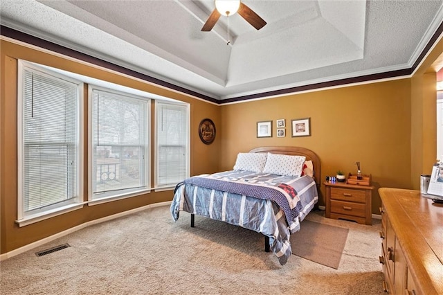 carpeted bedroom with a tray ceiling, visible vents, crown molding, and baseboards