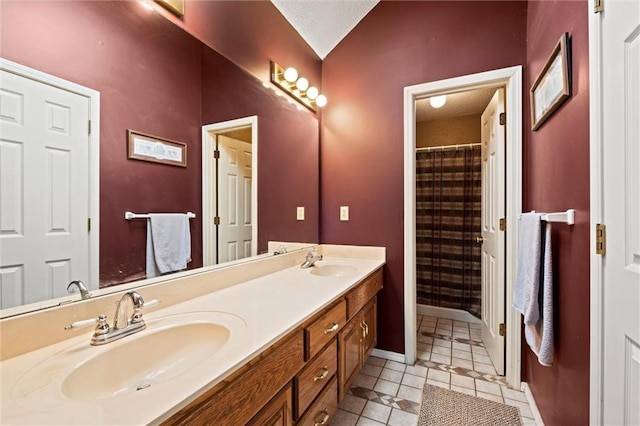 full bathroom with lofted ceiling, double vanity, baseboards, and a sink