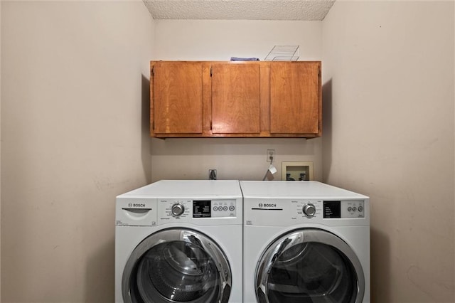 washroom featuring washer and dryer, cabinet space, and a textured ceiling