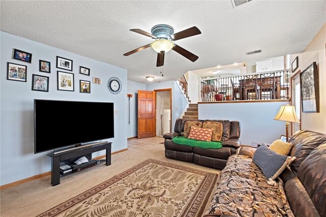 carpeted living area with baseboards, visible vents, ceiling fan, stairs, and a textured ceiling