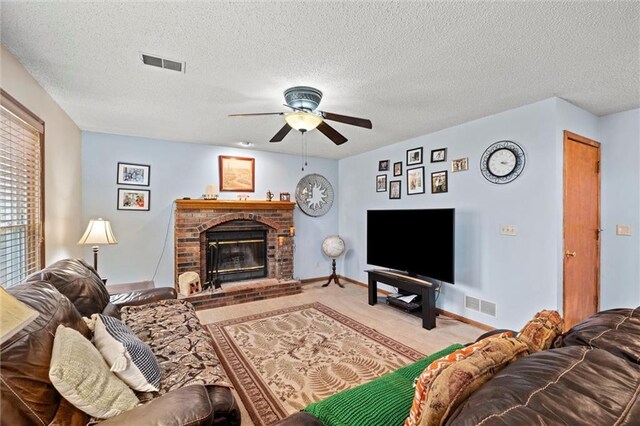 carpeted living area featuring a ceiling fan, a fireplace, visible vents, and a textured ceiling