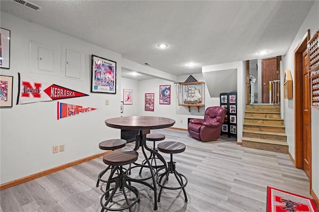 game room with light wood-style floors, visible vents, a textured ceiling, and baseboards