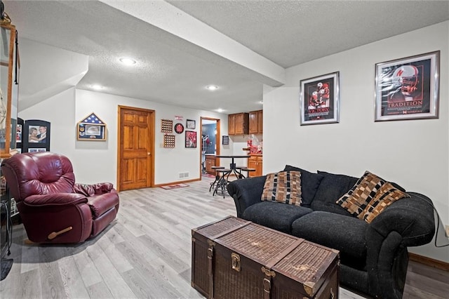 living room featuring visible vents, baseboards, light wood-style flooring, a textured ceiling, and recessed lighting