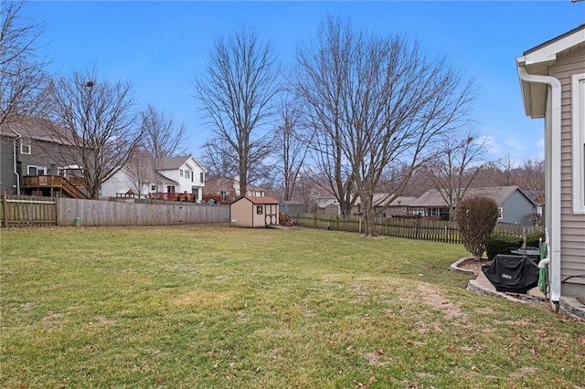 view of yard featuring a fenced backyard, a residential view, a storage unit, and an outbuilding