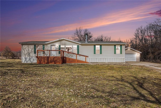 manufactured / mobile home with a yard, a wooden deck, a detached garage, and an outdoor structure