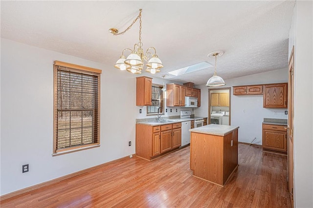 kitchen featuring a kitchen island, light countertops, light wood-style floors, independent washer and dryer, and white appliances