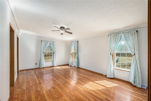 unfurnished room with plenty of natural light, light wood-style flooring, a textured ceiling, and crown molding