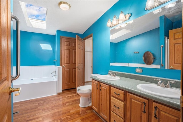 full bathroom featuring a sink, a garden tub, wood finished floors, and double vanity