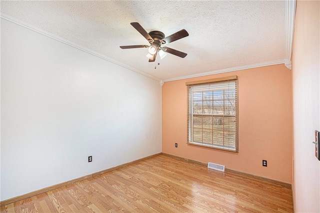 empty room featuring crown molding, light wood-style flooring, visible vents, and a textured ceiling