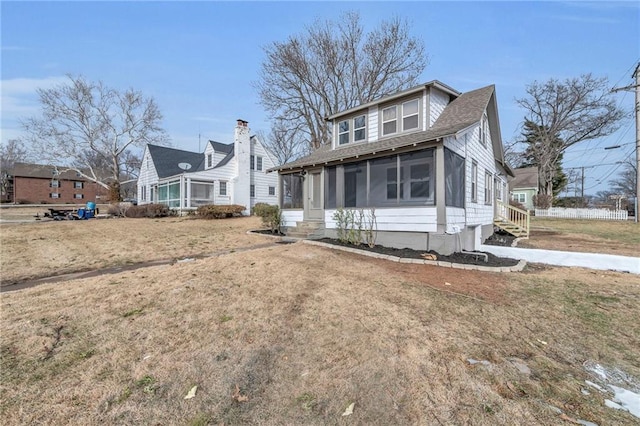 bungalow-style home featuring a shingled roof, a front yard, and a sunroom