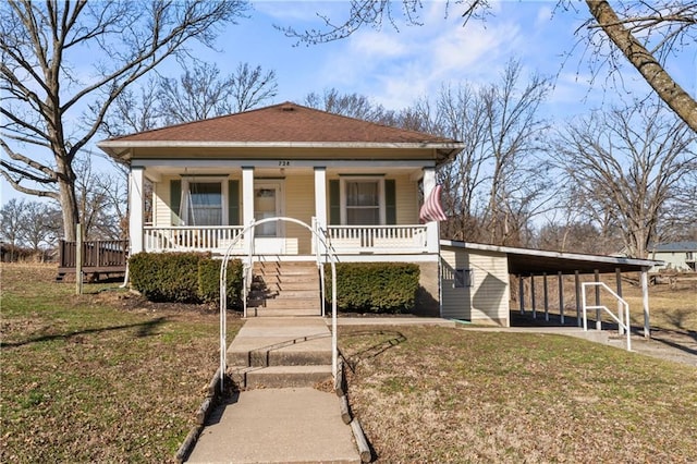 view of front facade with covered porch, a shingled roof, driveway, a carport, and a front lawn