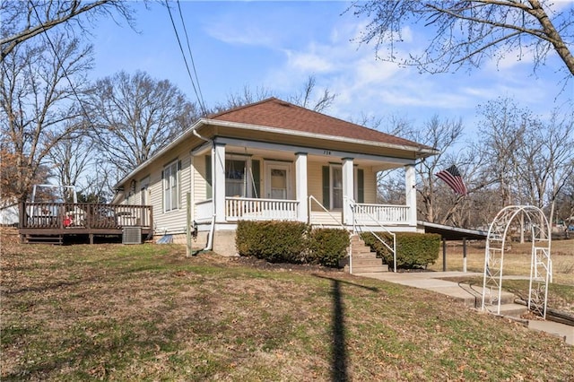 bungalow-style home featuring a porch, a front yard, central AC, a carport, and driveway