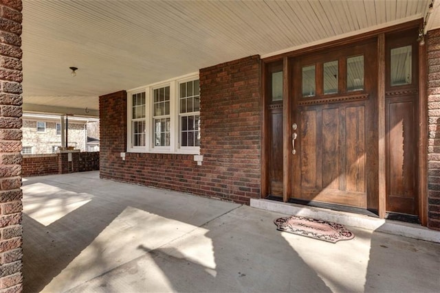 property entrance with covered porch and brick siding