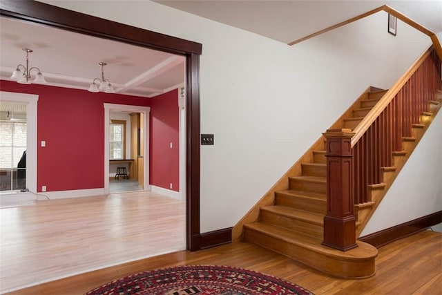 staircase with a chandelier, baseboards, and wood finished floors