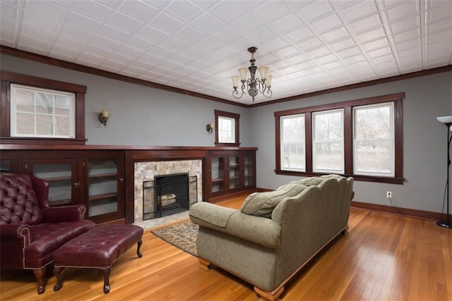 living area with ornamental molding, a fireplace, hardwood / wood-style floors, and baseboards