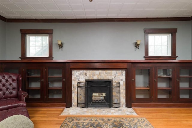 living room featuring a wealth of natural light, wood finished floors, and a stone fireplace