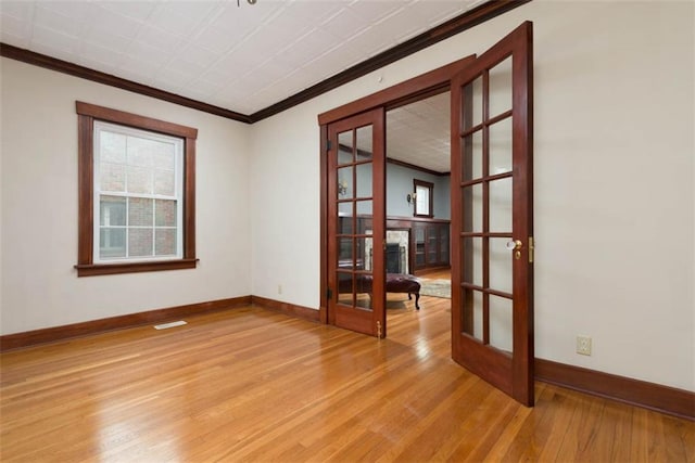 unfurnished room with light wood-style flooring, visible vents, baseboards, ornamental molding, and french doors