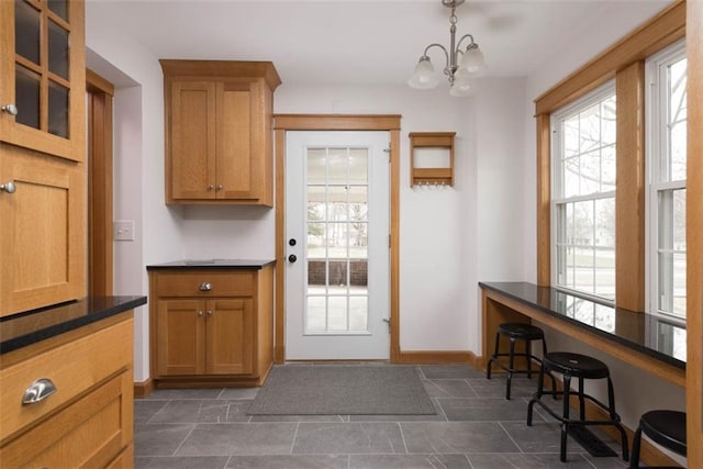 doorway to outside featuring an inviting chandelier and baseboards