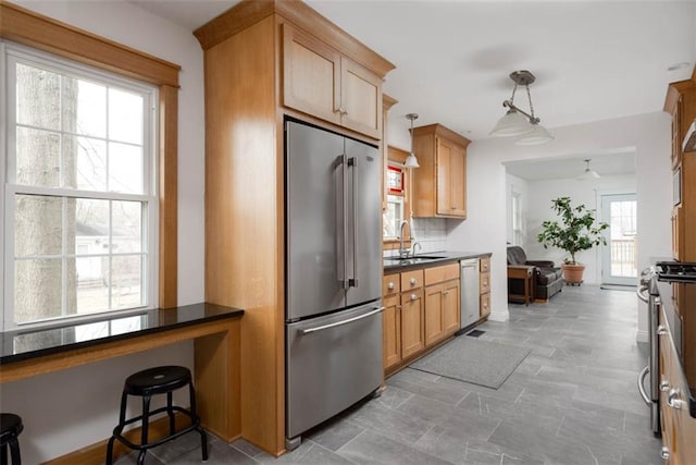 kitchen with stainless steel appliances, dark countertops, a sink, and decorative backsplash